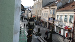 A street view with a building labeled "L'PASSO" and a sign for "El Lattino." - Casa Gotica Residence (Brasov)