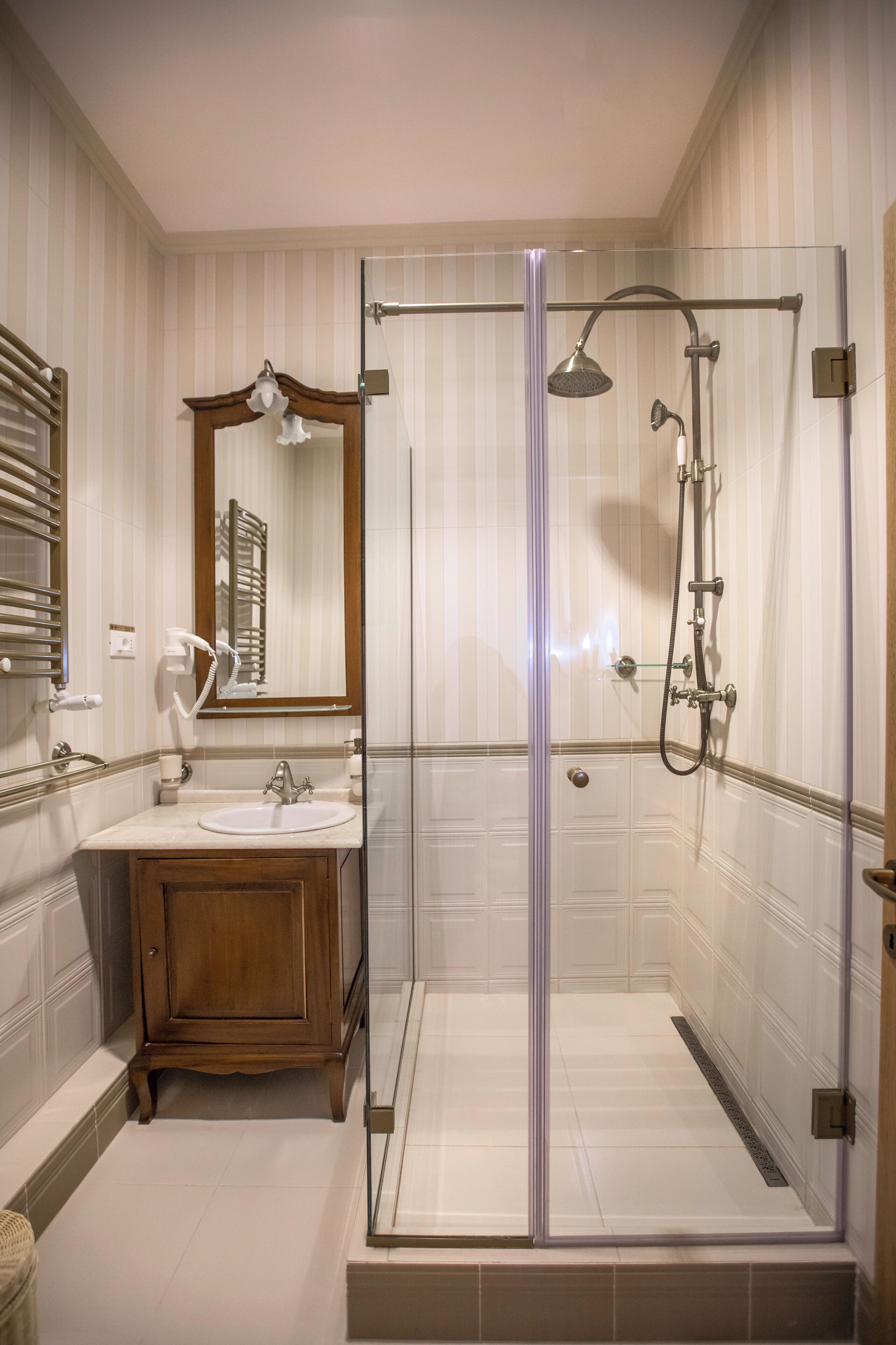 A modern bathroom with a glass-enclosed shower, a wooden vanity, and a large mirror.