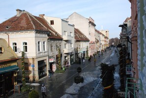 A street with buildings, a person walking, and a sign for a restaurant. - Casa Gotica Residence (Brasov)