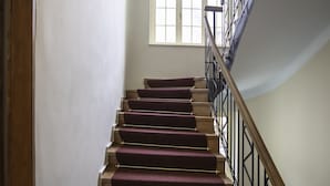 A staircase with wooden steps and a handrail, leading to a landing with a window. - Casa Gotica Residence (Brasov)
