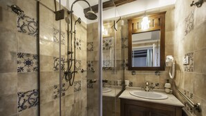 A bathroom with a glass-enclosed shower, a double sink vanity, and decorative tiles. - Casa Gotica Residence (Brasov)