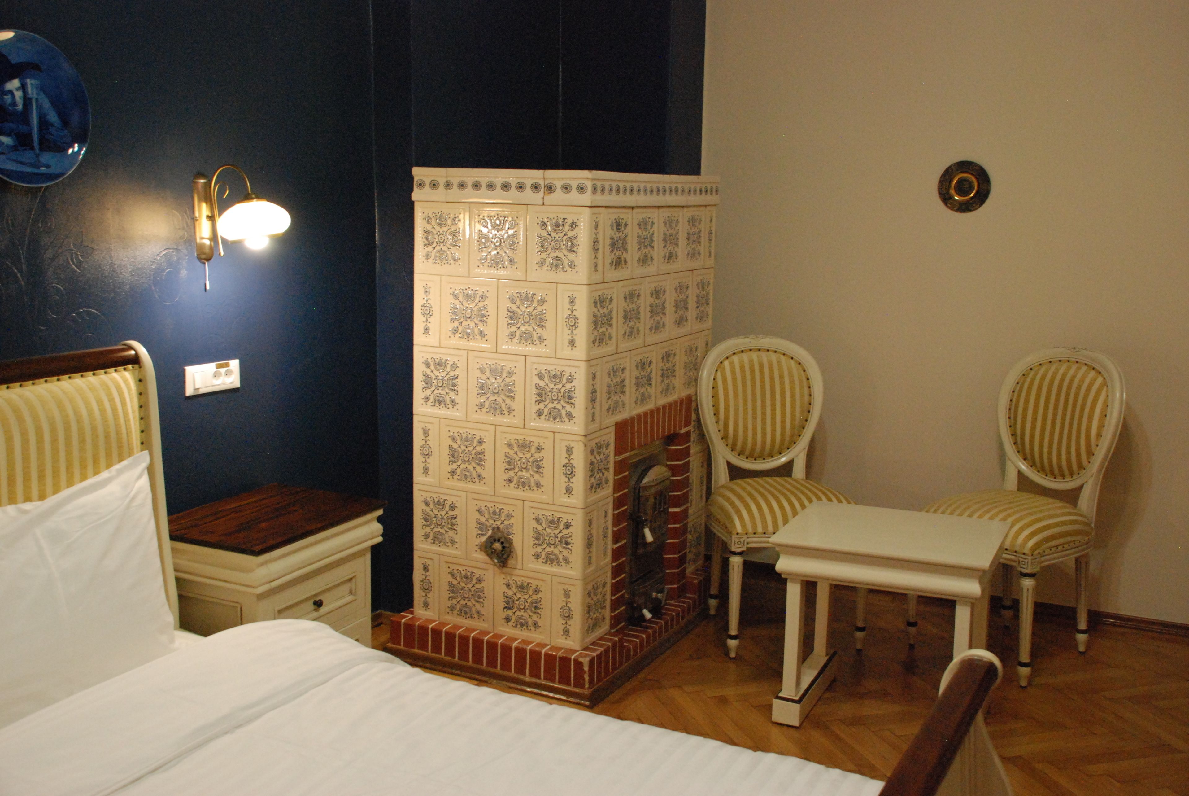 A bedroom with a bed, nightstand, wall-mounted light, and a decorative tiled partition.
