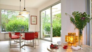 Uma cozinha moderna com área de jantar, janelas grandes e vista para o verde lá fora.