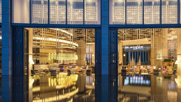 Eine großzügige Lobby mit spiegelndem Boden, Sitzbereichen und modernem Interieur.