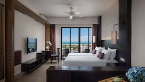 Ein modernes Hotelzimmer mit einem großen Bett, einem Fernseher, einem Schreibtisch und Blick aufs Meer.