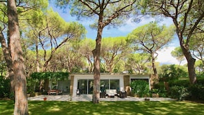 Een modern huis met een terras, omgeven door bomen.