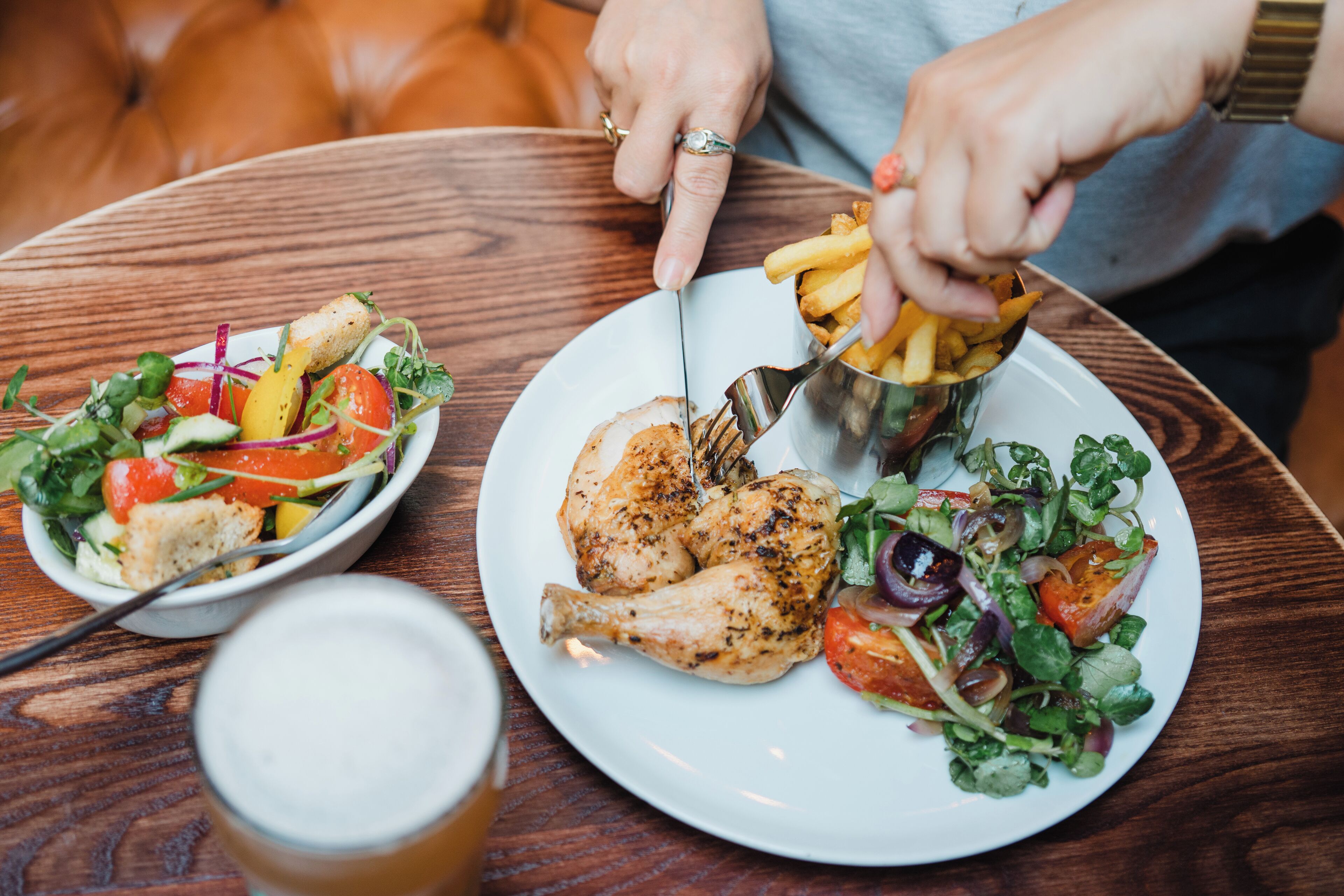Un tavolo da pranzo con un piatto di pollo alla griglia, un'insalata e un bicchiere di birra.