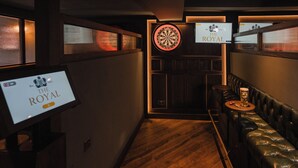 A narrow hallway with a dartboard and a sign reading "The Royal".