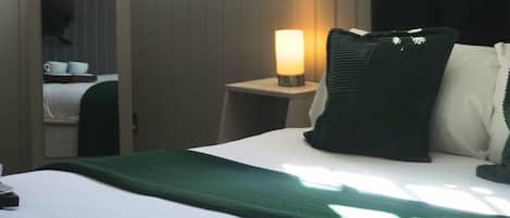 A hotel room with a bed, a bedside lamp, a window, and a view of the outside.