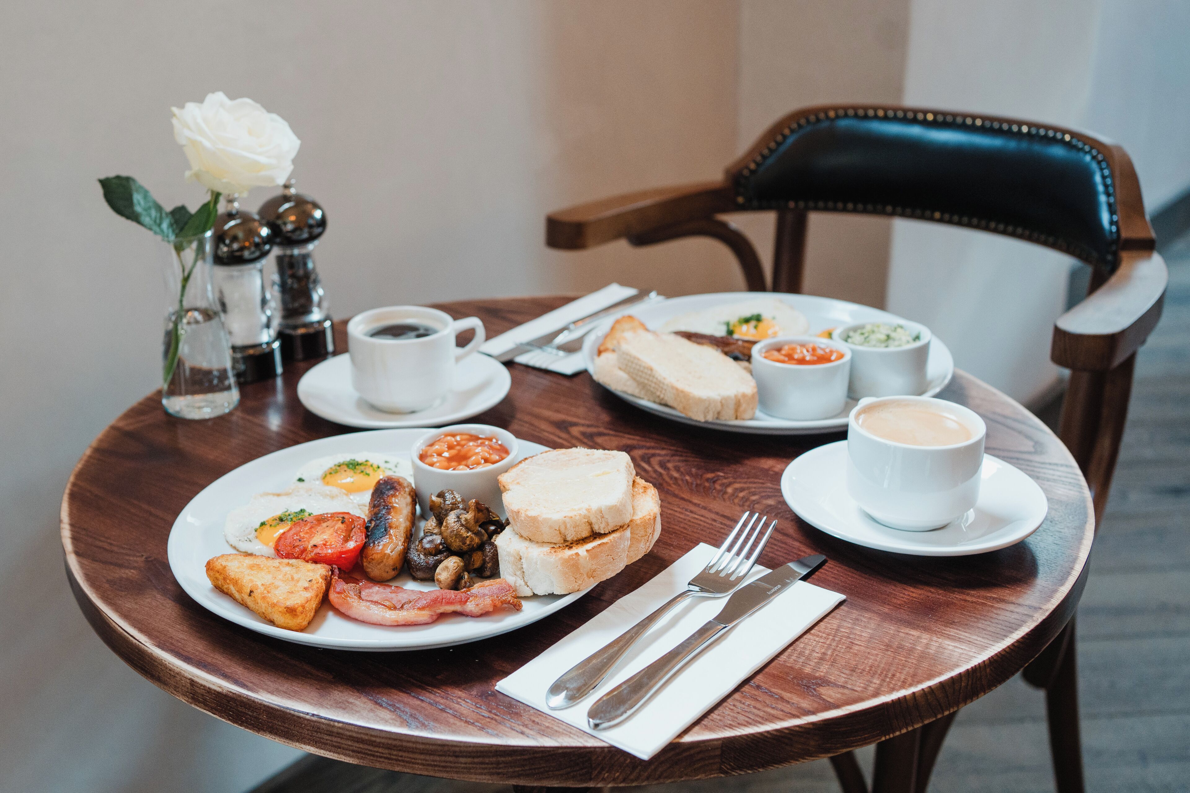 Une table de petit-déjeuner avec des assiettes contenant des œufs, des toasts, des haricots et du café.