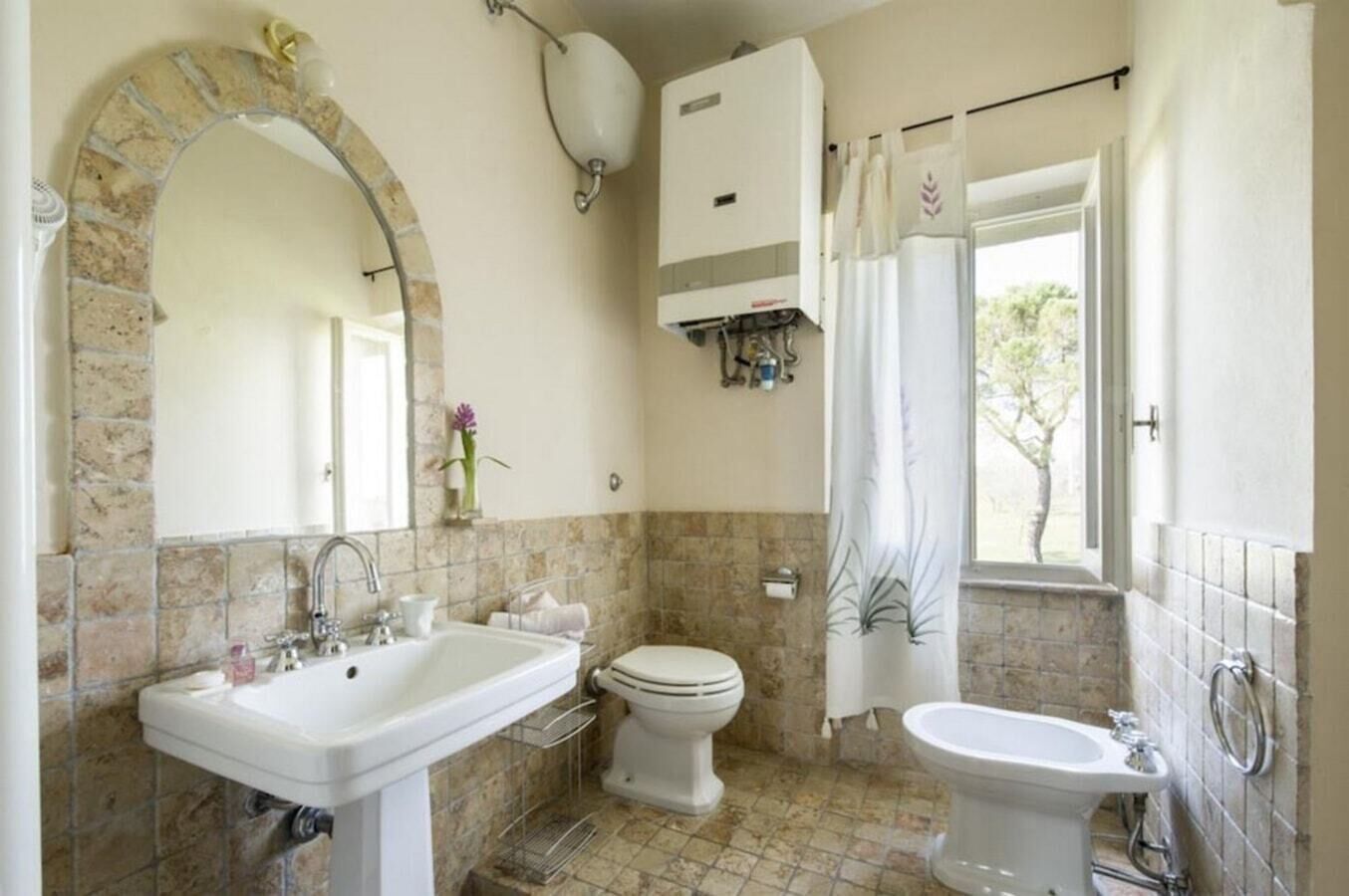 Un baño con lavamanos, inodoro, bidé y un espejo grande.