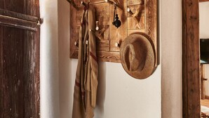A rustic interior with exposed wooden beams, a wooden door, and a wall-mounted coat rack with a hat and a key. - "Melkerhaus" bis 6 Personen mit Terrasse und Pool, 101m² (Wonneberg)
