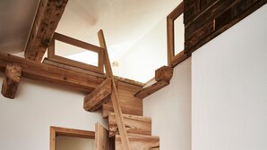 A wooden staircase leading to an upper level, with a door at the bottom and a light fixture above. - "Melkerhaus" bis 6 Personen mit Terrasse und Pool, 101m² (Wonneberg)