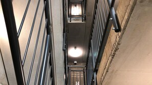 A narrow, metal-framed elevator shaft with a light fixture at the top. - Avaneo Hotel Marktredwitz (Marktredwitz)