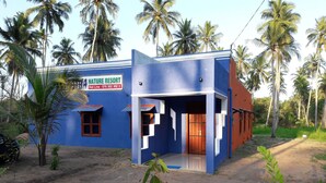 A nature resort with a blue building, a signboard, and palm trees in the background. - Ulpatha Nature Resort (Kobeigane)