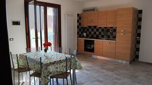 Comedor con una mesa dispuesta para cuatro, cocina con armarios de madera y un salpicadero a cuadros.