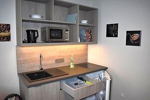 Una cocina compacta equipada con microondas, hervidor y pileta.