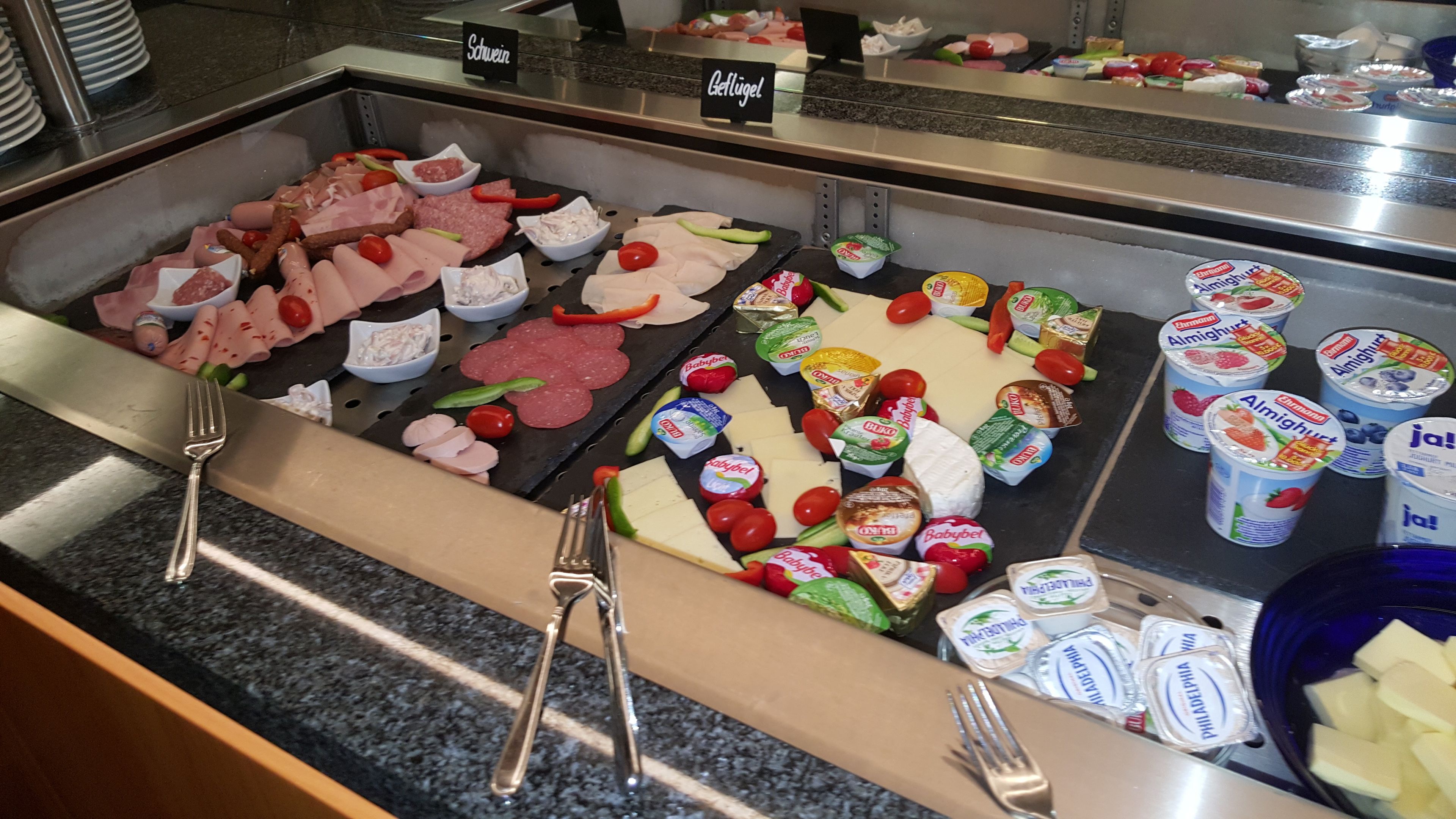 A buffet with various meats, cheeses, and dairy products.