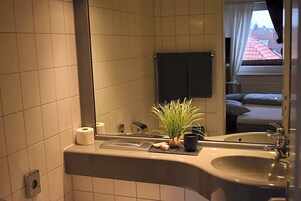 Ein Badezimmer mit Waschbecken, Spiegel, Handtuchhalter und einer Topfpflanze.
