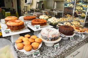 A bakery display with various cakes and pastries. - Hotel Casa Nova (Varzea Grande)