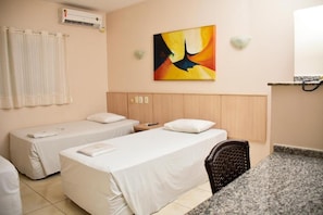 A hotel room with two single beds, a chair, a painting on the wall, and an air conditioning unit. - Hotel Casa Nova (Varzea Grande)