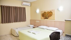 Habitación de hotel con cama, una silla, una mesa, aire acondicionado de pared y un cuadro.