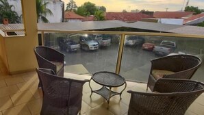 Un balcón con mobiliario de mimbre y vista a un estacionamiento.