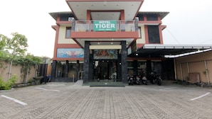 A hotel entrance with a sign reading "HOTEL TIGER" and a contact number. - Hotel Tiger Yogyakarta (Depok)