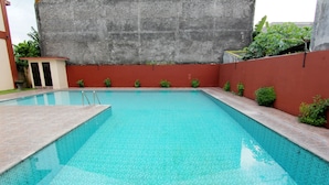 A rectangular swimming pool with a tiled floor and a surrounding wall. - Hotel Tiger Yogyakarta (Depok)