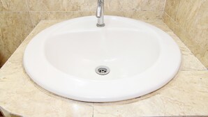 A bathroom sink with a chrome faucet and a drain. - Hotel Tiger Yogyakarta (Depok)
