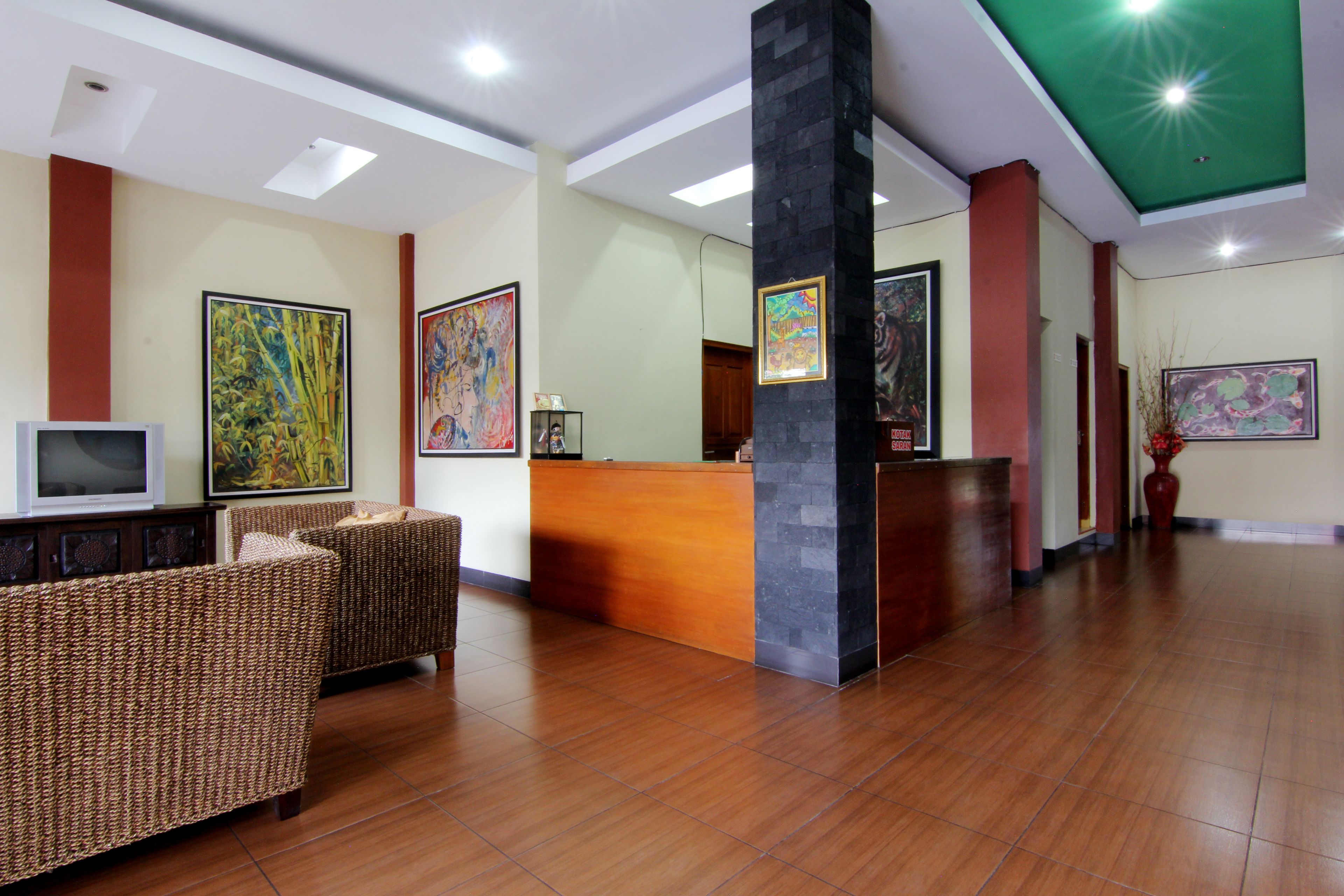 A lobby with a reception desk, two wicker sofas, and artwork on the walls.