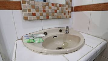 A bathroom sink with a mirror above it, surrounded by white tiles with brown borders.