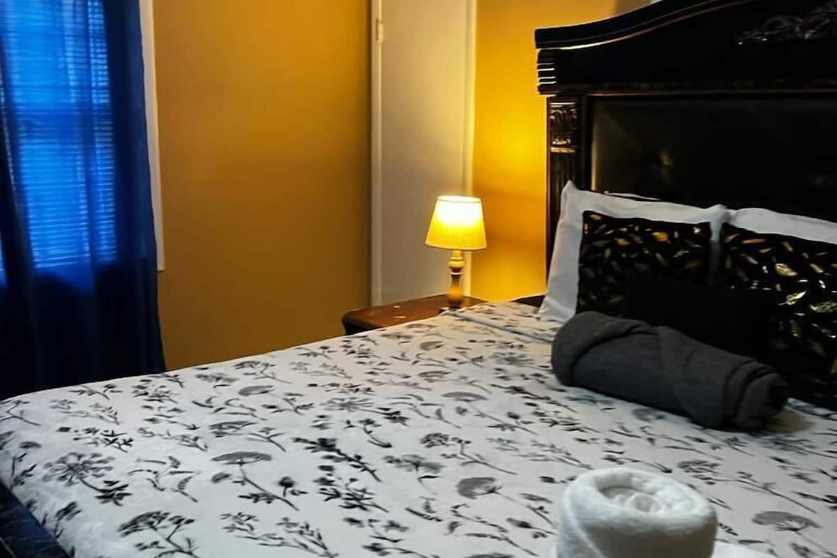 A hotel room with a bed, a nightstand, a lamp, and a folded towel on the bed.