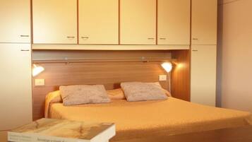 A bedroom with a bed, two bedside lamps, and a nightstand with books.