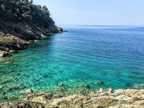 A rocky coastline with clear turquoise waters, a few people enjoying the view, and a distant horizon. - Agriturismo La Quiete (Levanto)