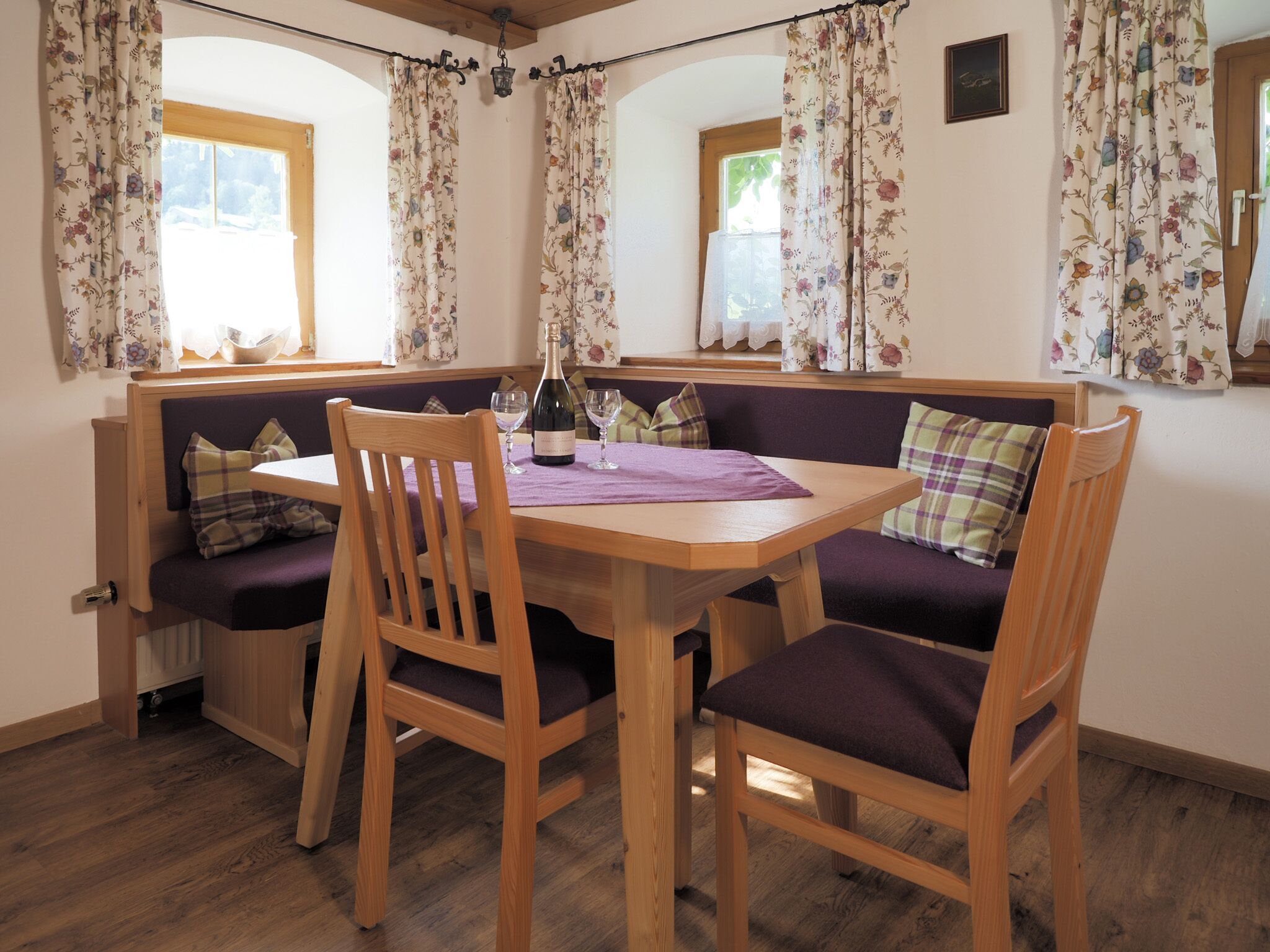 A cozy dining area with a wooden table, two chairs, and a bench with cushions.