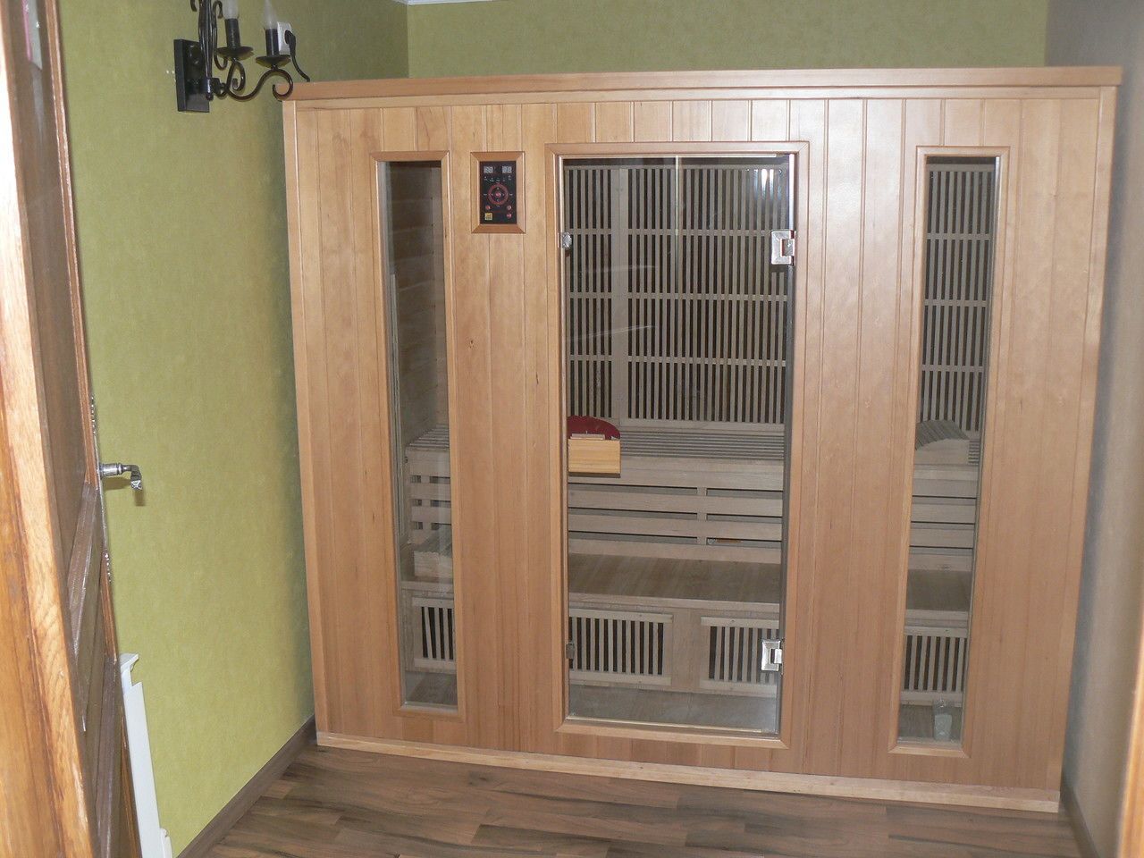 Een houten garderobe met twee deuren en een middenvak, een wandlamp en een houten vloer.