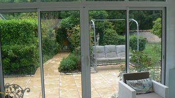 Un patio con un sofá de mimbre blanco, un sendero de piedra y abundante vegetación.