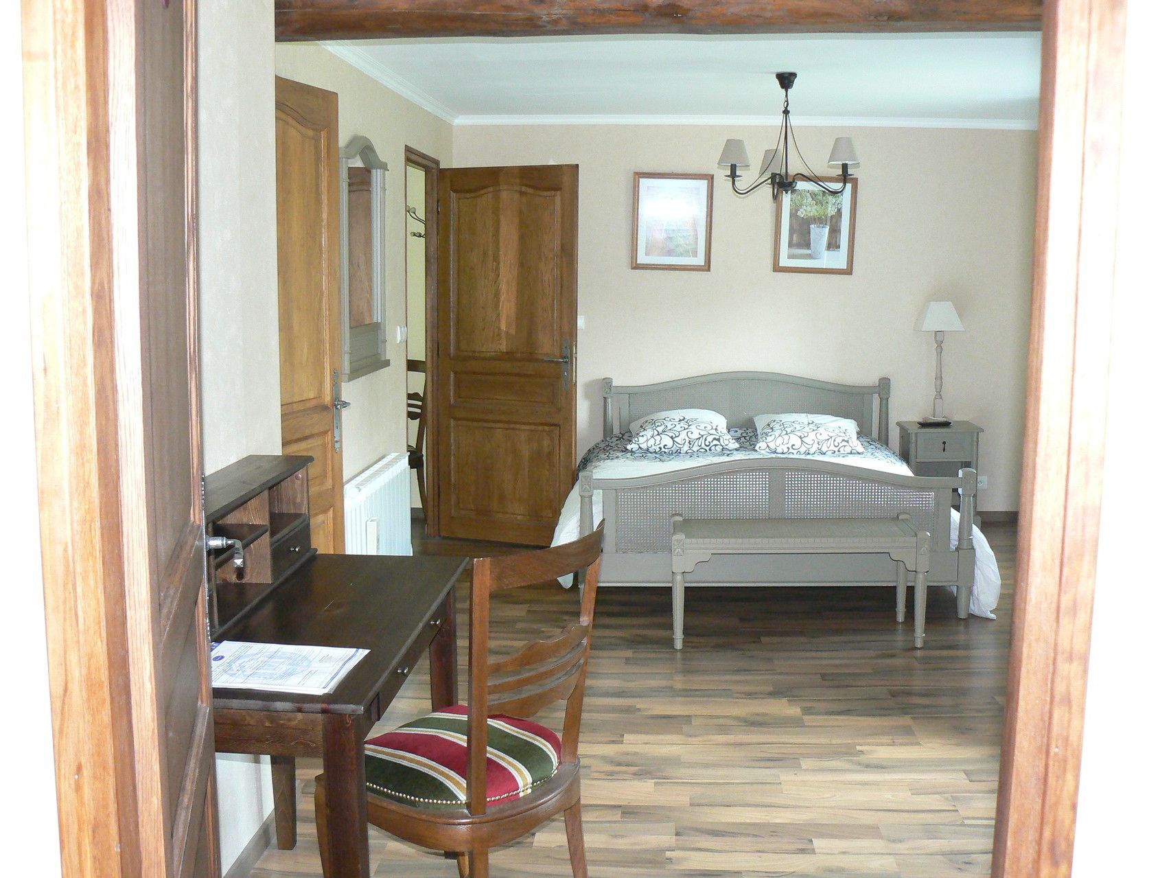Un dormitorio con cama, mesita de noche, una silla y una mesa de madera.