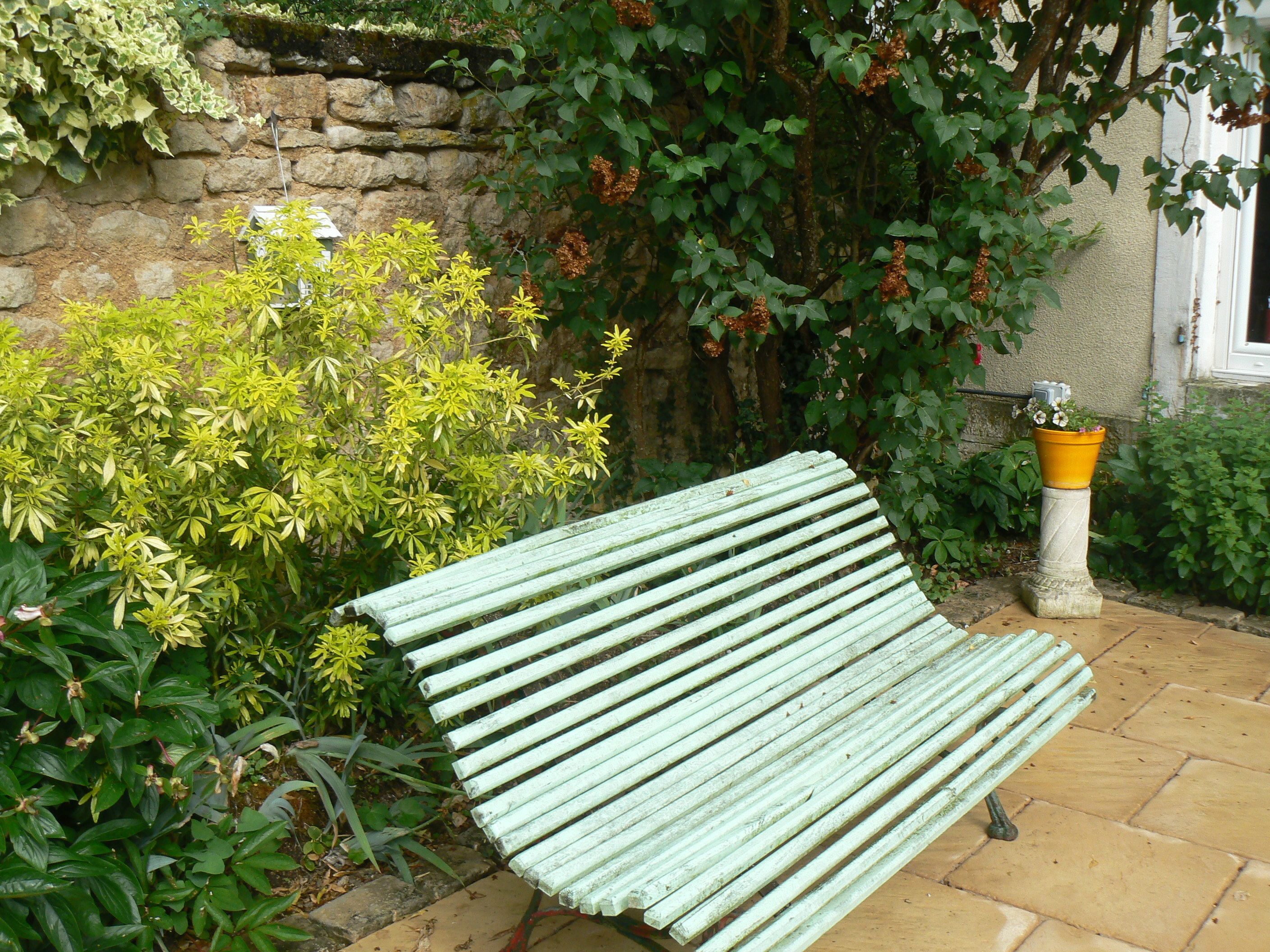 Un banco en un jardín con muro de piedra y diversas plantas.