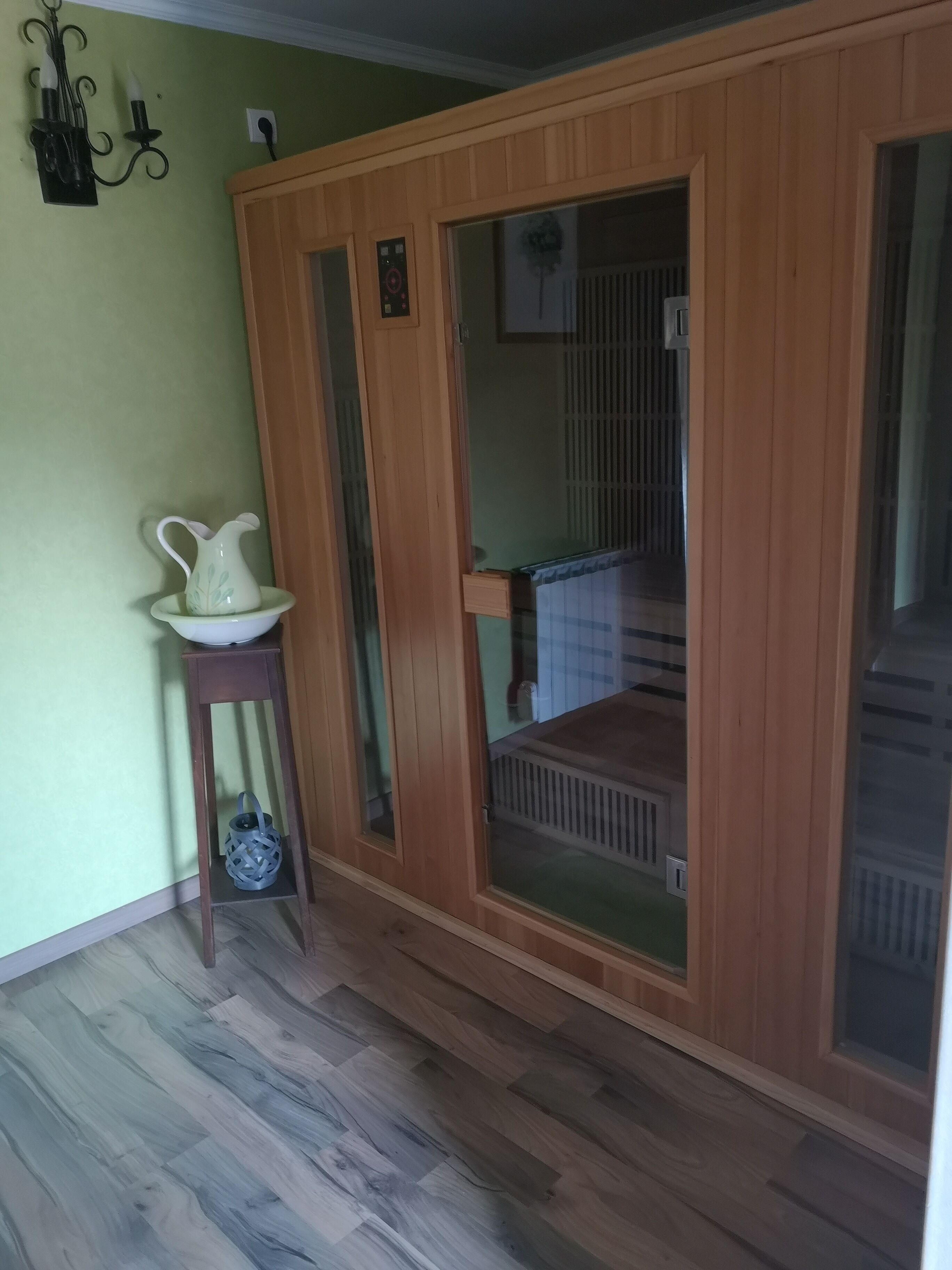 A room with a wooden wardrobe, a small table with a pitcher, and a radiator.