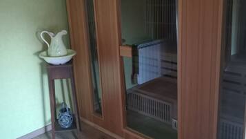 A room with a wooden wardrobe, a small table with a pitcher, and a radiator.