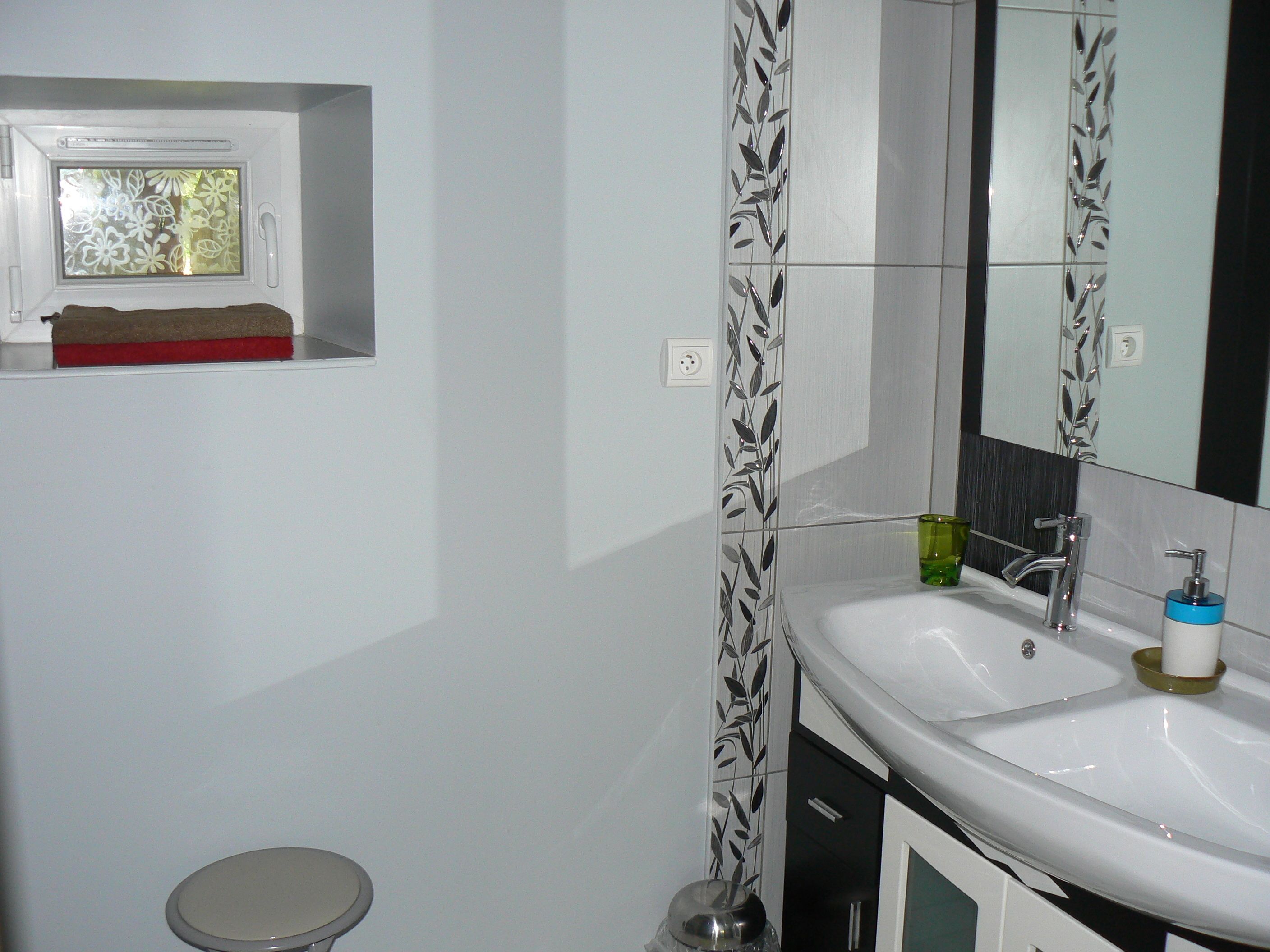 A bathroom with a white sink, a mirror, and a toilet.