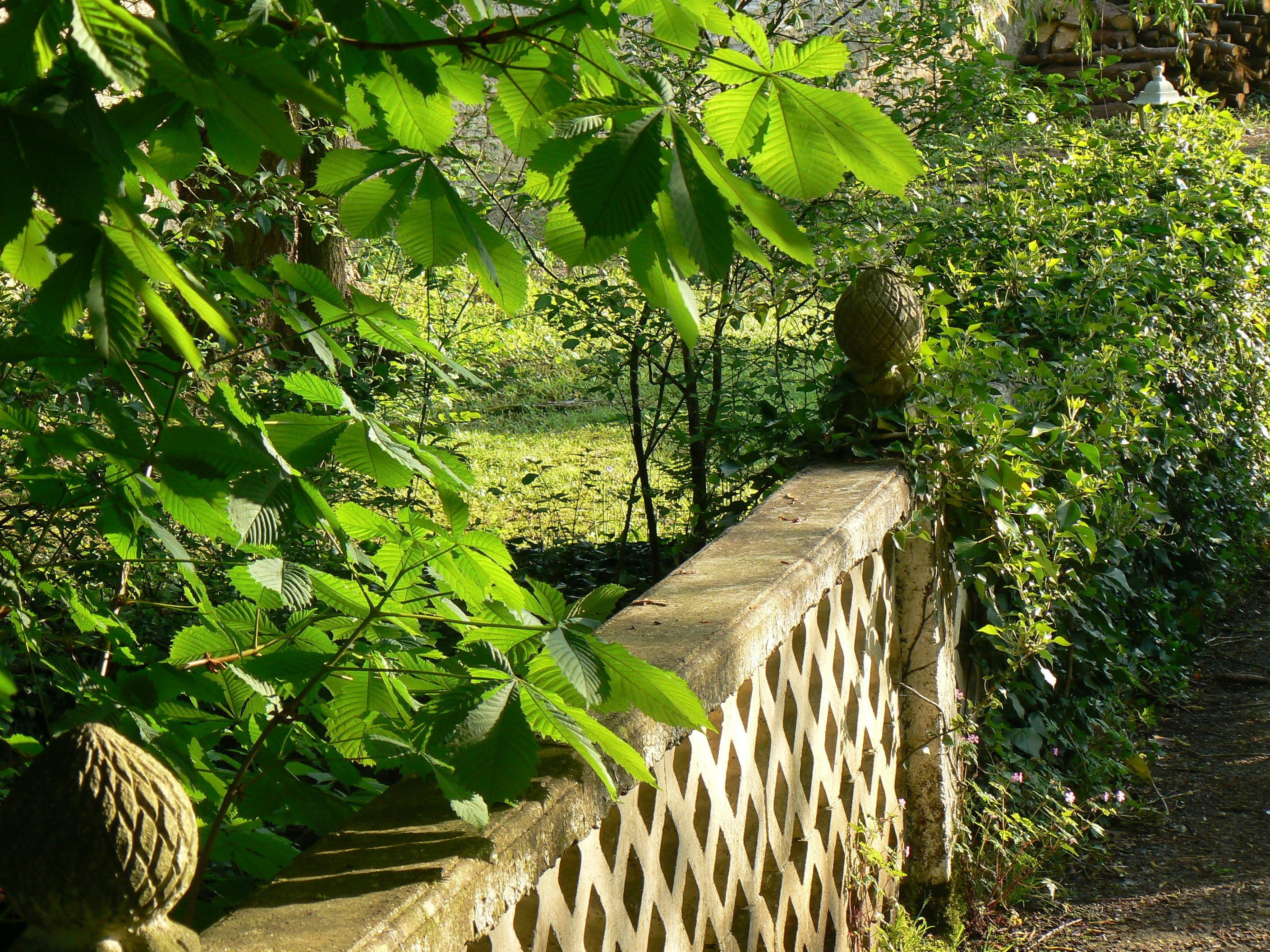 A stone bridge with a lattice design, surrounded by lush greenery and trees.