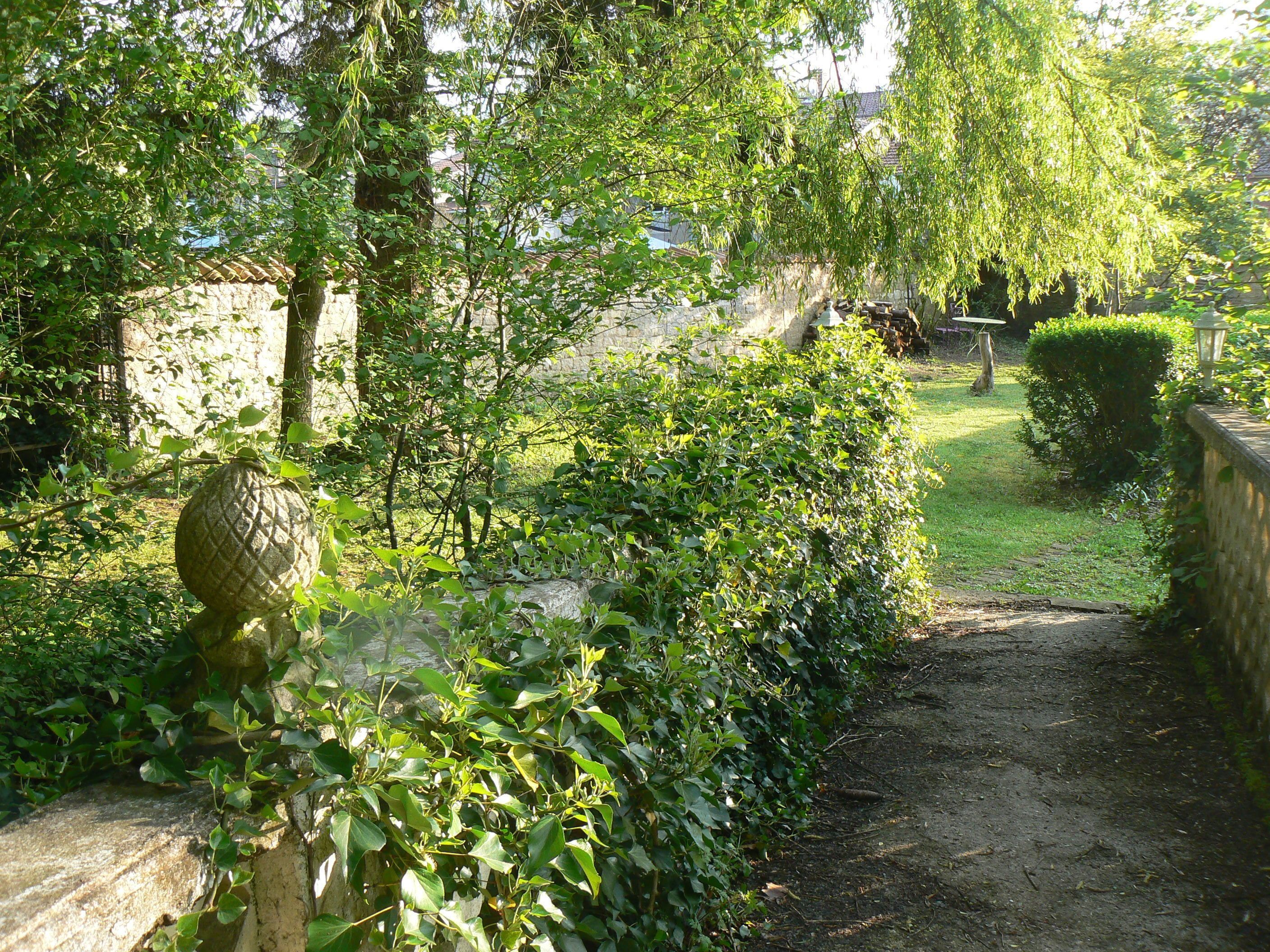 A garden pathway with stone walls and lush greenery.