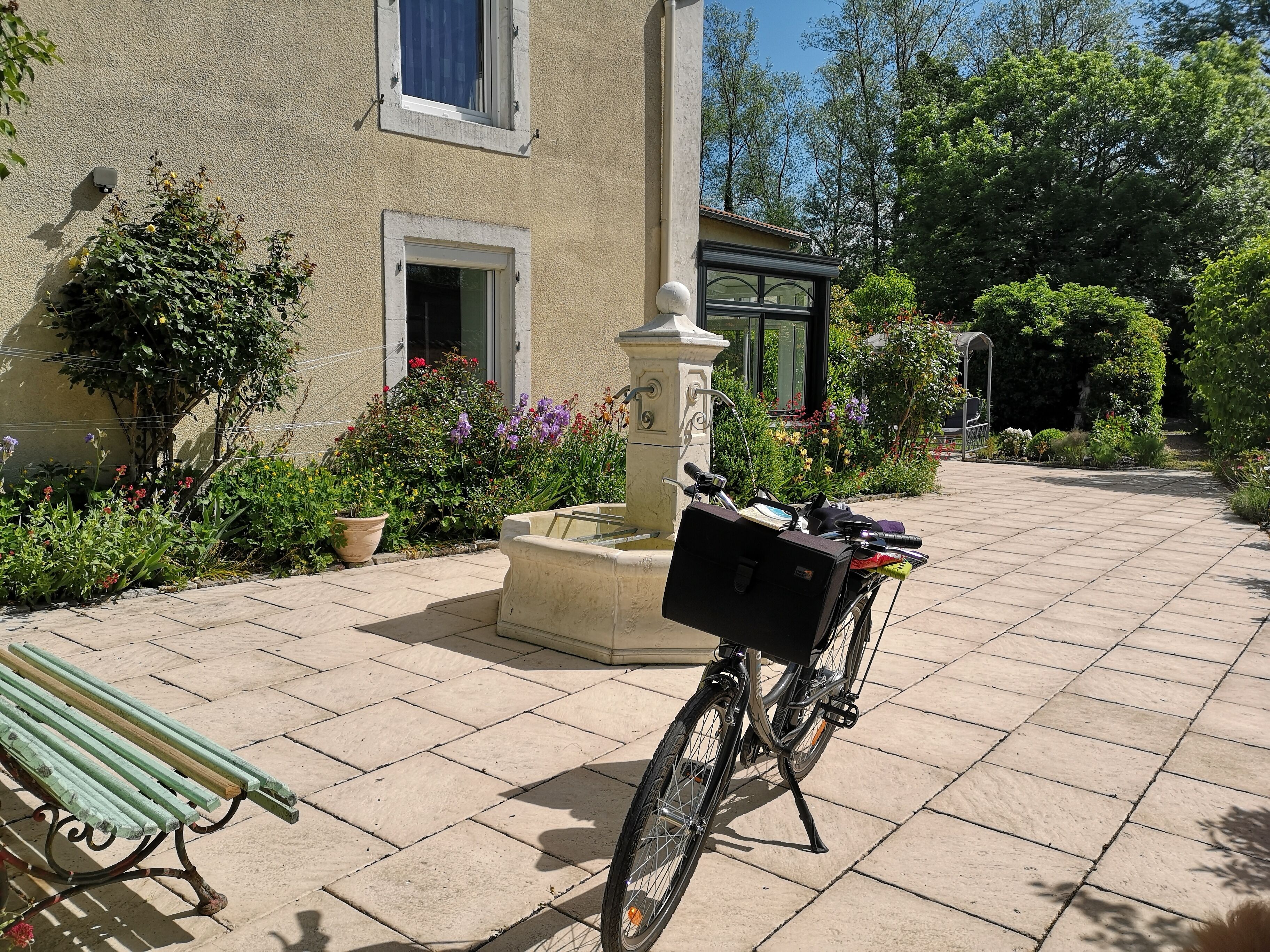 A courtyard with a bicycle, a bench, and a fountain.