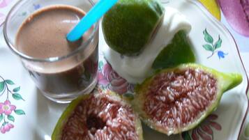 A plate with a glass of chocolate drink, a lime half, and a slice of green fruit.