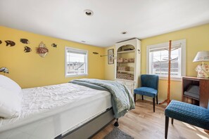 Un dormitorio con cama, una silla, un escritorio y una estantería.