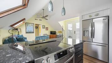 Una cocina moderna con estufa integrada, refrigerador de acero inoxidable y lámparas colgantes.