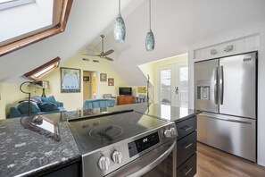 Una cocina moderna con estufa integrada, refrigerador de acero inoxidable y lámparas colgantes.
